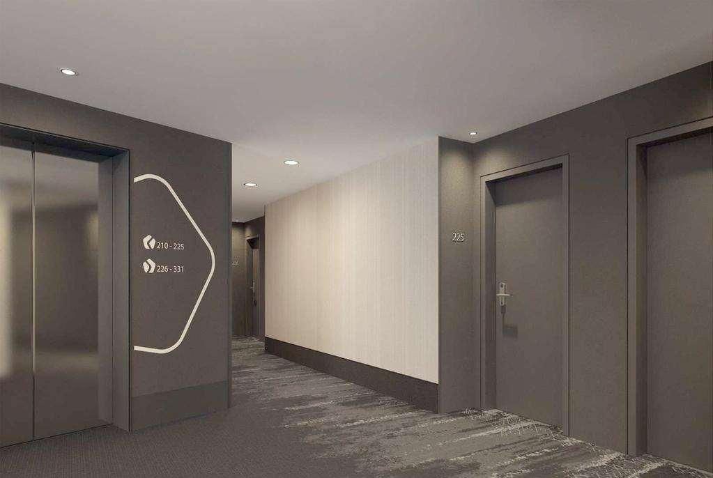 Hyperion Hotel Muenchen Dalaman gambar The photo shows a modern hotel corridor. On the left side, there is an elevator with a sleek design, and next to it are wall graphics or signage. The corridor has a neutral color scheme, primarily gray with a light beige wall. Doors to guest rooms ar